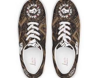 May include: A pair of white canvas low-top sneakers with a brown and black leopard print design. The shoes feature a white circle with the text "Black Lives Matter" and a raised fist in the center.
