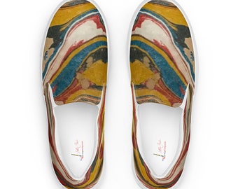 May include: A pair of white canvas slip-on shoes with a colorful abstract pattern. The pattern features swirls of yellow, red, blue, and black.