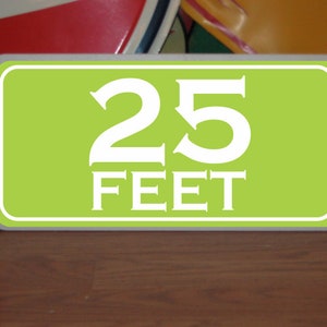 May include: A green sign with white text that reads "25 FEET".