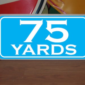 May include: A blue sign with white text that reads "75 YARDS".