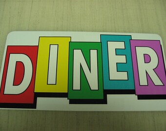 Puede incluir: Un letrero colorido con la palabra "DINER" escrita en bloques individuales. Cada letra es blanca con un contorno negro y está sobre un fondo de color diferente: rojo, amarillo, verde, azul y morado.