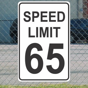 Op de afbeelding: Witte snelheidsbegrenzingsbord met zwarte tekst en cijfers. Het bord geeft "SPEED LIMIT 65" aan.