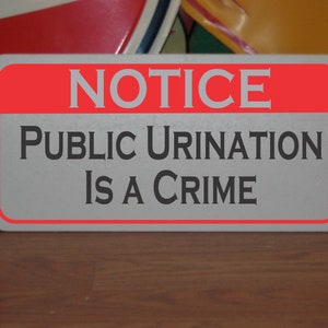 Puede incluir: Un letrero rojo y blanco con el texto "NOTICE PUBLIC URINATION IS A CRIME" en letras negras.
