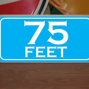 May include: A blue and white sign with the text "75 FEET" in white lettering.