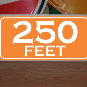 May include: Orange sign with white text that reads "250 FEET".