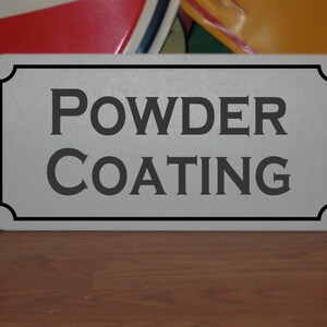 Puede incluir: Un letrero rectangular blanco con borde negro y el texto "POWDER COATING" en letras negras.