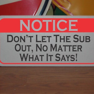 Może przedstawiać: Biały znak z czerwoną obwódką i tekstem "NOTICE DON'T LET THE SUB OUT, NO MATTER WHAT IT SAYS!" w kolorze czarnym.