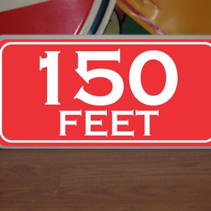 May include: Red rectangular sign with white text that reads "150 FEET".
