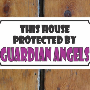 Puede incluir: Un cartel blanco con borde negro y esquinas redondeadas. El cartel dice "This house protected by guardian angels" en texto negro y morado.