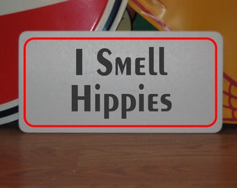 May include: White rectangular sign with red border, featuring the text "I Smell Hippies" in black bold letters.