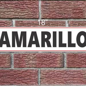 May include: White rectangular sign with a red border, reading "AMARILLO" in black bold letters. The sign is 18 inches wide and 6 inches tall.