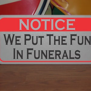 Puede incluir: Un letrero gris con borde rojo y el texto "NOTICE WE PUT THE FUN IN FUNERALS".