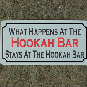 May include: White sign with black border and text that reads "What happens at the hookah bar stays at the hookah bar". The word "hookah" is in red.