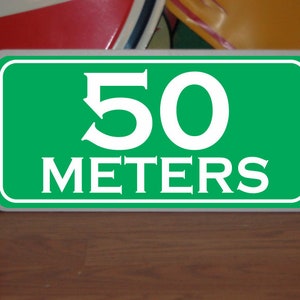 May include: Green sign with white text that reads "50 meters".