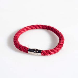 May include: A red rope bracelet with a silver magnetic clasp.