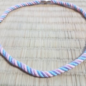 Può includere: Una collana di corda intrecciata rosa e blu con una chiusura argentata.