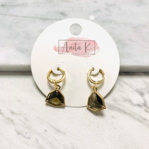 May include: Gold hoop earrings with a dangling geometric brown gemstone. The earrings are on a white card with the text "Anita K Styling Life".