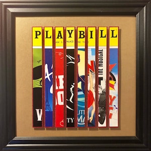 Puede incluir: Una obra de arte enmarcada que presenta un collage de carteles de programas de teatro coloridos para varios musicales de Broadway. Los carteles est&aacute;n dispuestos verticalmente y la palabra "PLAYBILL" est&aacute; escrita en letras amarillas en la parte superior.