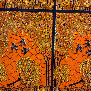 以下が含まれることがあります： オレンジとブルーの生地に、スタイリッシュな木と鳥の繰り返しパターンが施されています。木は黄色の葉を持ち、鳥は黒です。生地は織り込まれた質感です。