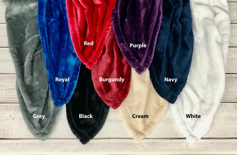 May include: A variety of plush blankets in different colors, including grey, royal blue, red, burgundy, purple, navy, cream, and white. The blankets are arranged in a row, with the colors alternating.