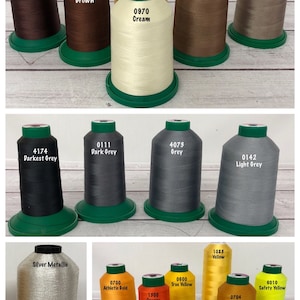 May include: Assortment of spools of thread in various colors, including dark brown, chocolate brown, cream, tan, light tan, darkest grey, dark grey, grey, light grey, silver, athletic gold, true yellow, safety yellow, orange, and Vegas gold. The spools are labeled with their corresponding color names and numbers.