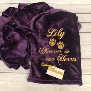 May include: Purple fleece blanket with gold embroidery that reads "Lily Forever in our Hearts" with three paw prints. The blanket is folded and has a small tag that reads "In Deepest Sympathy".