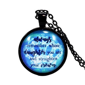 May include: A black chain necklace with a round glass pendant. The pendant has a blue and green background with a white crown and the text "always remember whose daughter you are and straighten your crown".