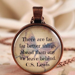 May include: A round copper-toned pendant necklace featuring a butterfly graphic background with the black text: There are far, far better things ahead than any we leave behind. C.S. Lewis. The pendant has a smooth glass dome and a matching copper chain.