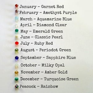 May include: A chart listing birthstones for each month of the year. January is Garnet Red, February is Amethyst Purple, March is Aquamarine Blue, April is Diamond Clear, May is Emerald Green, June is Classic Pearl, July is Ruby Red, August is Peridot Green, September is Sapphire Blue, October is Milky Opal, November is Amber Gold, December is Turquoise Green, and Peacock is Rainbow.