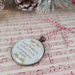 Pu&ograve; includere: Un ciondolo ornamentale rotondo color bronzo con un inserto bianco e testo color oro che recita: I will honor Christmas in my heart, & try to keep it all the year. ~Dickens. Il ciondolo &egrave; fissato a uno spago da cucina rosso e bianco.