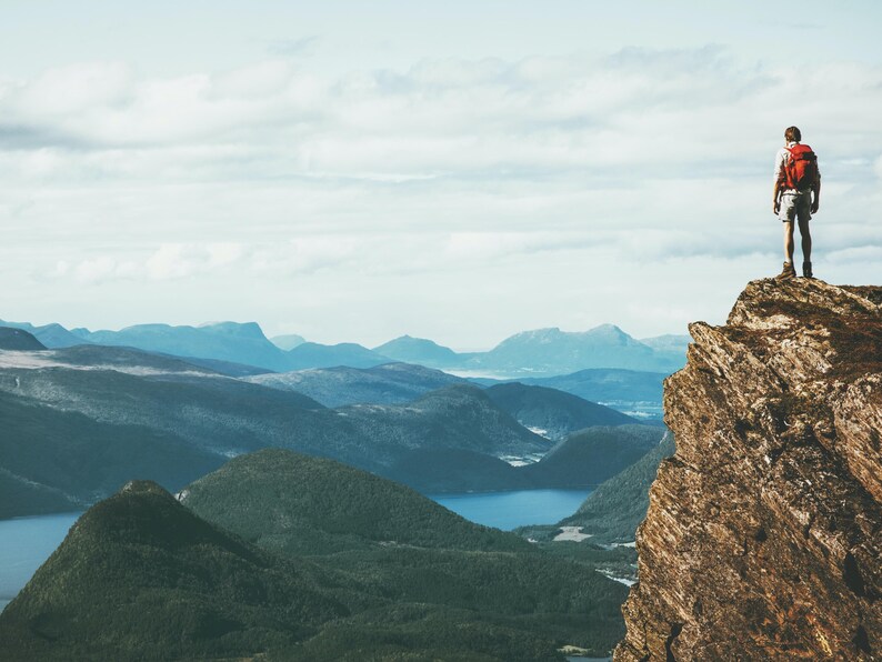 a man standing on top of a mountain with a backpack