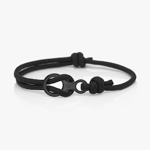 May include: A black rope bracelet with a black metal clasp. The clasp has the text "88°" engraved on it.