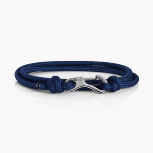 Puede incluir: Un brazalete de cuerda azul marino con un cierre plateado.