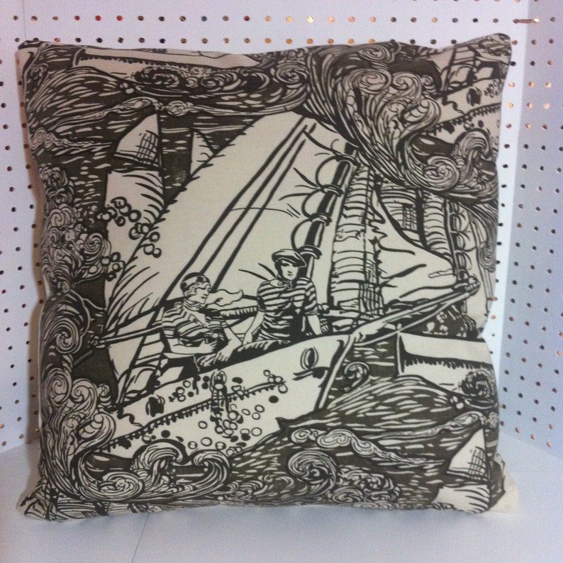 May include: A black and white pillow with a nautical theme. The pillow features a sailboat with two people on board, surrounded by waves and clouds. The pillow is made of a soft, comfortable fabric.