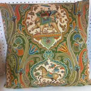 Puede incluir: Una almohada de tiro de color verde, naranja y azul con un patrón de paisley y una imagen bordada de un elefante que lleva a dos personas en su espalda.