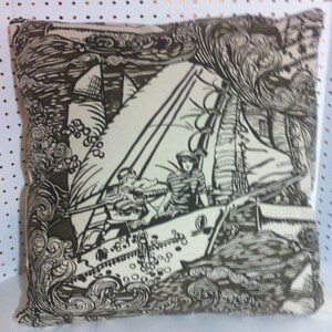 May include: A cream-colored pillow with a black and white illustration of a sailboat with two people on board. The sailboat is sailing through a stormy sea with waves crashing around it. The background is a dark gray color.