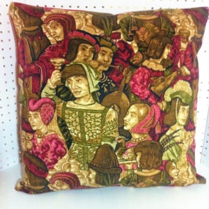 May include: A decorative pillow with a vintage tapestry design featuring a group of people in medieval clothing. The fabric is a rich brown and gold with accents of red and pink.