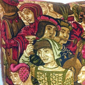 May include: A colorful tapestry pillow featuring a medieval scene with figures in red, gold, and green clothing. The figures are playing musical instruments and appear to be in a festive setting.
