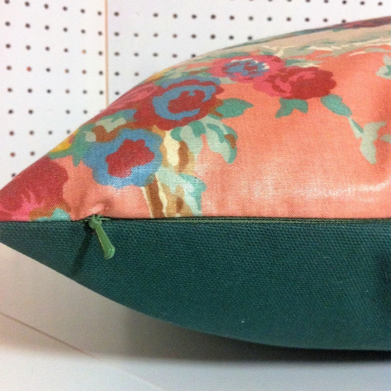 May include: A pink pillow with a floral pattern and a green zipper. The pillow is made of a soft, comfortable fabric and has a hidden zipper closure.