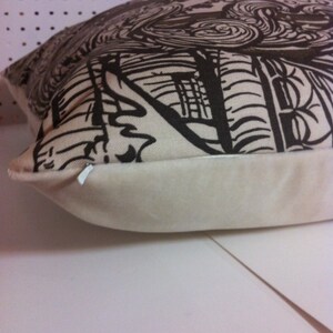 May include: A white pillow with a brown and black abstract design. The pillow has a white zipper and a white backing.