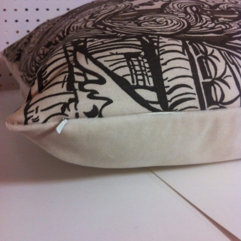 May include: A white pillow with a brown and black abstract design. The pillow has a white zipper and a white backing.