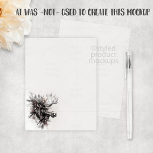 Puede incluir: Una maqueta de papeler&iacute;a con una tarjeta blanca con una ilustraci&oacute;n detallada de una cabeza de alce con cornamenta y acentos florales. Tambi&eacute;n hay un sobre a juego y un bol&iacute;grafo transparente. El texto "AI WAS -NOT- USED TO CREATE THIS MOCKUP" est&aacute; en la parte superior.