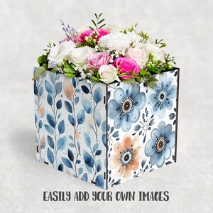 May include: A square wooden floral arrangement box filled with white, pink, and fuchsia roses, and greenery. The box is decorated with blue floral and leaf patterns. The text "EASILY ADD YOUR OWN IMAGES" is printed on the bottom of the box.