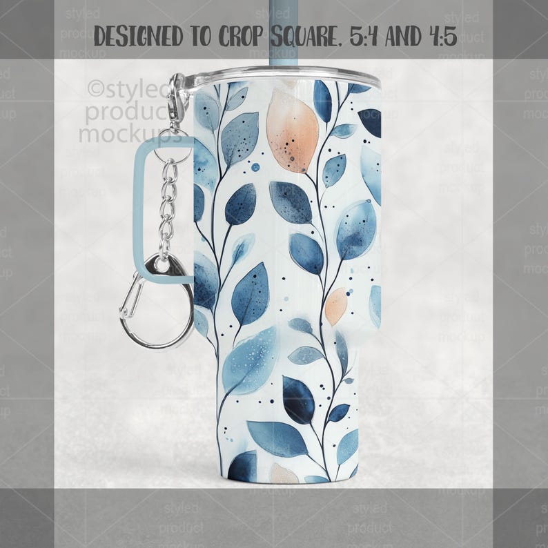 May include: A white tumbler with a blue and peach watercolor leaf design. The tumbler has a light blue handle and a silver carabiner clip. The text "DESIGNED TO CROP SQUARE. 5:4 AND 4:5" is at the top.