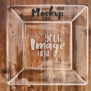 May include: A clear glass serving plate with a raised edge. The plate is on a wooden surface. The text "PLATE MOCKUP LARGE" and "YOUR IMAGE HERE" is etched into the glass.