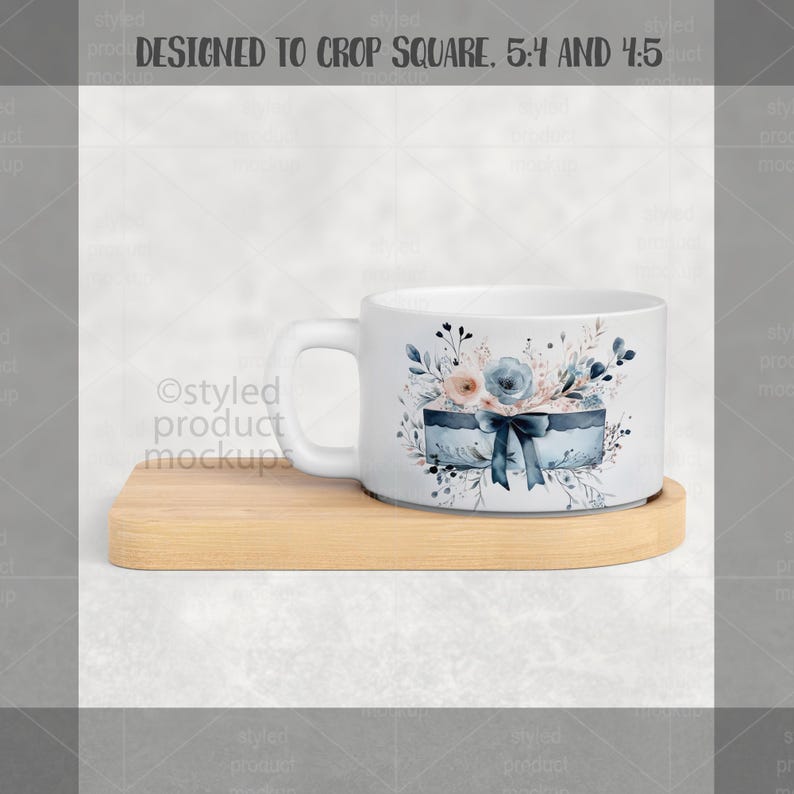 May include: White ceramic mug with a floral design featuring blue and peach flowers, a blue gift box, and a dark blue bow. The mug sits on a light brown wooden coaster. The mug is designed to crop square, 5:4 and 4:5.