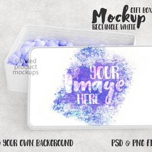 Könnte beinhalten: Weißer rechteckiger Geschenkbox-Mockup mit einem Aquarell-Design in den Farben Lila, Blau und Weiß. Der Text "YOUR IMAGE HERE" ist über das Design gelegt. Die Box ist geöffnet und mit hellblauen Bonbons gefüllt.