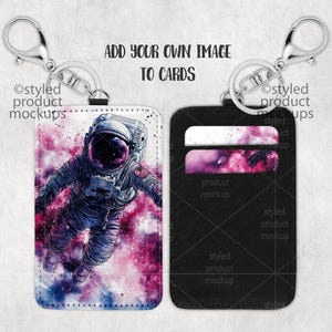 May include: Two keychains with card holders. One keychain has a white card holder with a colorful astronaut illustration. The other keychain has a black card holder with two card slots.