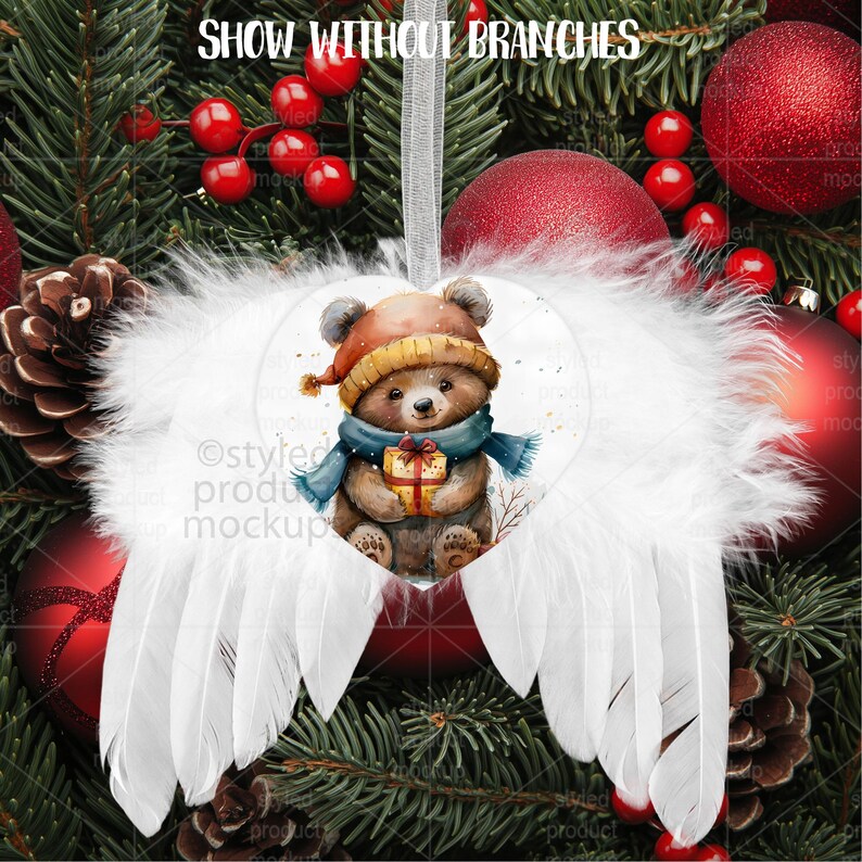 May include: A Christmas ornament featuring a watercolor illustration of a teddy bear wearing a hat and scarf, holding a gift. The bear is set against white feather wings. The ornament hangs from a silver ribbon, with the text "SHOW WITHOUT BRANCHES" at the top.