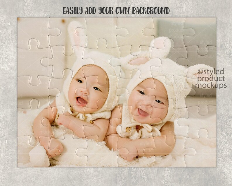 May include: Two babies wearing white bunny costumes with ears, lying on a white fuzzy blanket. The babies are looking at the camera and smiling. The image is a jigsaw puzzle with a white background.